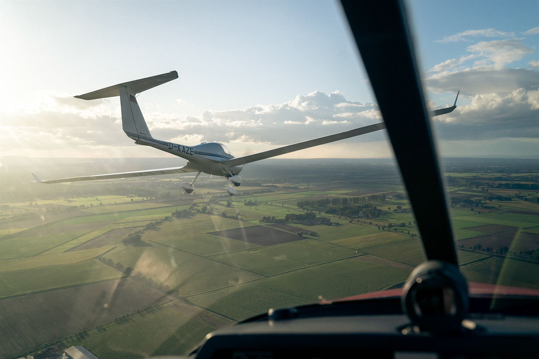 Segelflugzeug über Feldern, gesehen durch die Cockpithaube