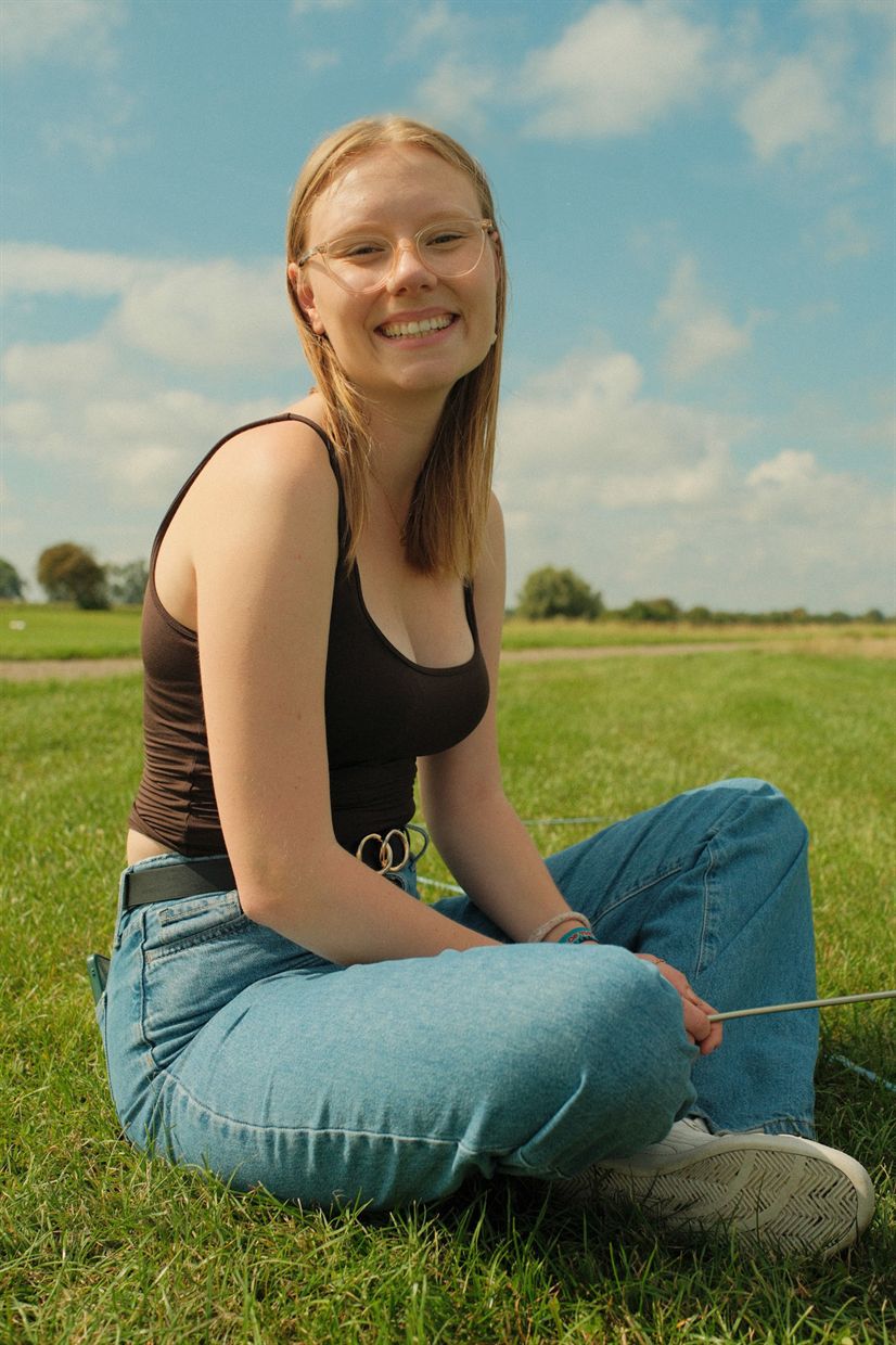 Lächelnde junge Frau sitzt im Gras