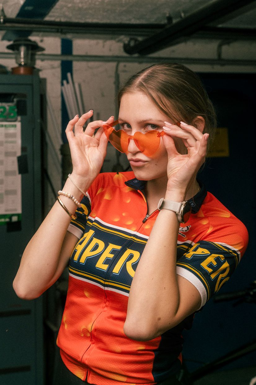 Frau mit orangefarbener Sonnenbrille und Radtrikot in einer Werkstatt