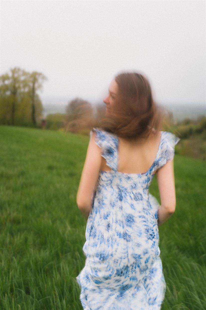 Frau im Sommerkleid von hinten auf einer Wiese