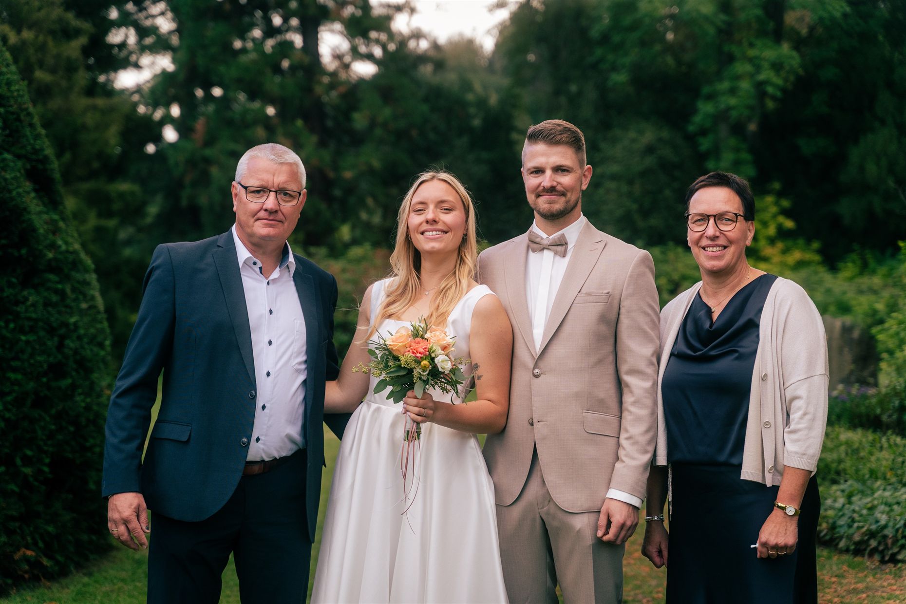 Brautpaar mit zwei Gästen im Park