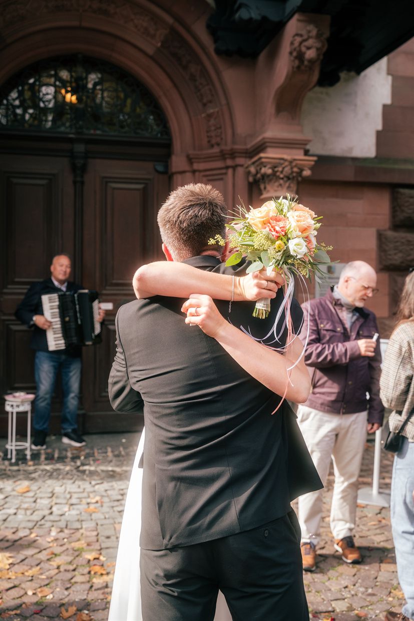 Brautpaar umarmt sich vor dem Standesamt